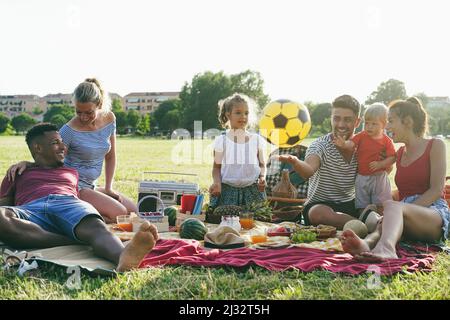 Glückliche Familien, die Spaß haben, Picknick im Park im Freien in den Sommerferien zu machen - Fokus auf afrikanisches Männergesicht Stockfoto