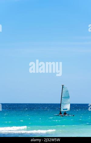 Schöne Seestücke, ein Boot mit weißem Segel auf türkisfarbenen Wellen. Exotisches karibisches Meer und klarer blauer Himmel. Yachting und Segeln. Hochwertige Fotos Stockfoto