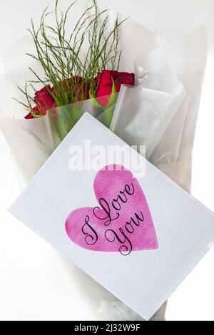 Ein Strauß roter Rosen mit „I Love You“ Valentinskarte für den Valentinstag auf weißem Hintergrund Stockfoto