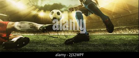 Nahaufnahme von Fußballbeinen, Fußballspieler in Aktion, Bewegung im Stadion mit Taschenlampen und überfüllten Tribünen. Konzept des Sports, des Wettbewerbs Stockfoto