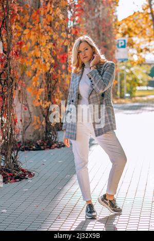 Vertikal der blondBusiness Dame Frau zu Fuß Stein gemauerte Straße im Park, Garten nach der Arbeit. Efeu-Liane aus Ahorn. Schließen Stockfoto