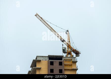 Crane on eine Spitze der Konstruktion eines Komplexes aus monolithischen, mehrstöckigen Gebäuden. Stockfoto