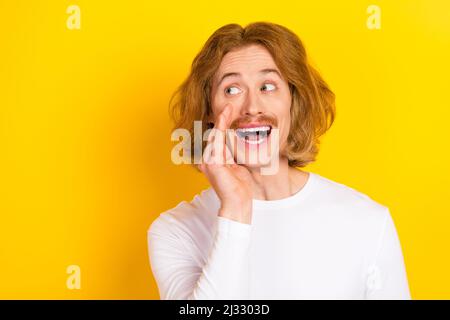 Foto von lustigen sorglosen Mann suchen leeren Raum sprechen über neue Werbung Förderung isoliert auf gelbem Hintergrund Stockfoto