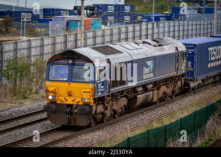 Direkte Bahndienste der Klasse 66 - 66429 mit einem kompletten Satz Tesco-Waggons verlassen DIRFT Stockfoto