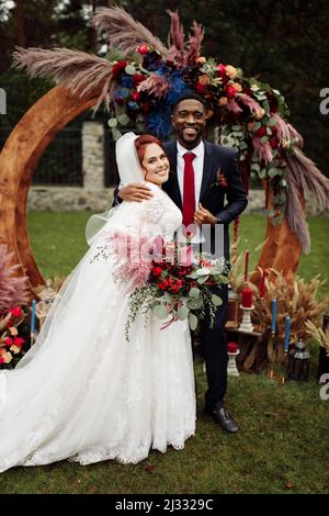 Überglücklich Paar stehen in der Nähe dekorierten Bogen, entzückendes Paar auf Hochzeitszeremonie, schöner afroamerikanischer Mann mit schönen weißen Frau genießen glückliche Mutter Stockfoto