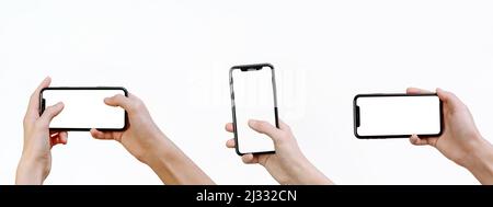 Junger Mann hält ein Smartphone mit einem Mockup auf weißem Hintergrund. Webbanner. Smartphone-Modell. Satz von Händen halten ein modernes Smartphone in unterscheiden Stockfoto