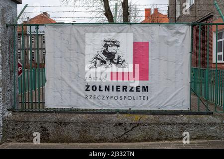 Danzig, Polen. 03. März 2022. Ein Banner mit der Aufschrift „werde ein polnischer Soldat“, das am Eingang des polnischen Militärstützpunkts in Braniewo zu sehen ist. Russland marschierte am 24. Februar 2022 in die Ukraine ein und löste damit den größten militärischen Angriff in Europa seit dem Zweiten Weltkrieg aus Bis zu 10 Millionen Ukrainer sind aus ihren Häusern geflohen, entweder aus dem Land oder in sicherere Gebiete innerhalb der Ukraine. Es wird angenommen, dass etwa 3 Millionen Flüchtlinge die Grenzen in Nachbarländer überschritten haben. (Foto von Mateusz Slodkowski/SOPA Images/Sipa USA) Quelle: SIPA USA/Alamy Live News Stockfoto