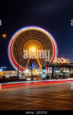 Hamburg, Deutschland-11232021:Nachtaufnahme des Eingangs zum hamburger Volksfest DOM mit dem Riesenrad und Lichtspuren. Stockfoto