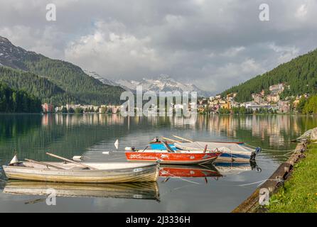 Ruderboote auf dem St. Moritzersee im Frühjahr mit St. Moritz Bad im Hintergrund, Graubünden, Schweiz. Stockfoto