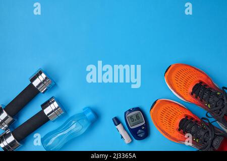 Orangefarbene Turnschuhe, Metallhanteln, eine Plastikflasche mit Trinkwasser Stockfoto