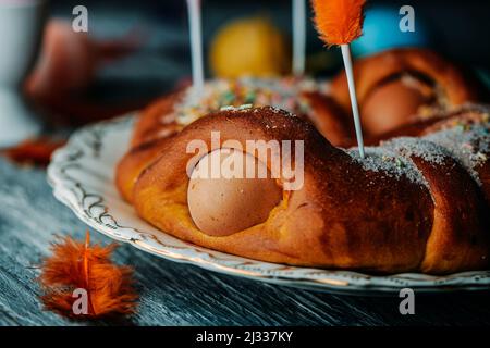 Nahaufnahme eines traditionellen mona de pascua, einem Kuchen, der am Ostermontag in Spanien gegessen wird und mit hart gekochten Eiern und Federn in verschiedenen Farben verziert ist Stockfoto
