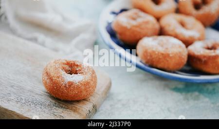 Ein Teller mit einigen Rosquillas, typisch spanischen Donuts mit Zucker bestreut, auf einem Tisch, in einem Panorama-Format als Webbanner zu verwenden Stockfoto