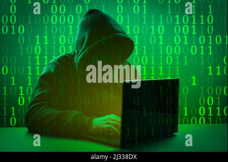 Hacker-Angriff. Computerhacker codieren auf der Tastatur. Gesichtsloser anonymer Computerhacker mit Kapuze auf dunkelgrünem Hintergrund. Internetkriminalität und elektronische b Stockfoto