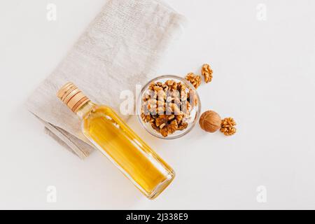 Walnuss oder Olivenöl in Glas Flasche, ganze große geschälte Walnusskern mit dünner Schale auf weißem Hintergrund. Gesunde Ernährung für das Gehirn. Frische Walnüsse zurück Stockfoto