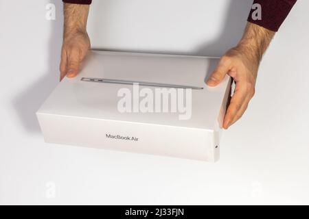 Saratov, Russland - 26. Februar 2022: Halten Schutzverpackung mit neuen modernen Macbook Air 13 Zoll mit M1 Prozessor topview, weißer Hintergrund Stockfoto