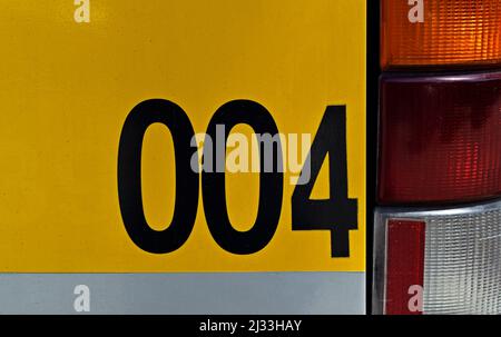 Nummer 004 auf metallischer Busoberfläche gedruckt Stockfoto
