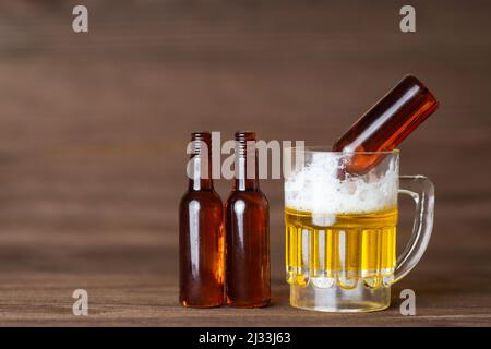 Leere Bierflaschen stehen neben einem Miniatur-Bierkrug. Konzept für mäßigen Alkoholkonsum. Stockfoto