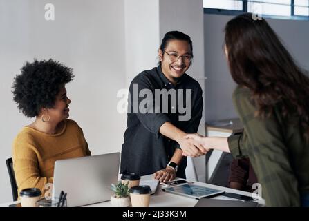 Es war ein Vergnügen, Geschäfte mit Ihnen zu machen. Eine kurze Aufnahme einer Gruppe junger Geschäftsleute, die sich mit einem Händedruck begrüßten, bevor sie sich hinsetzten Stockfoto