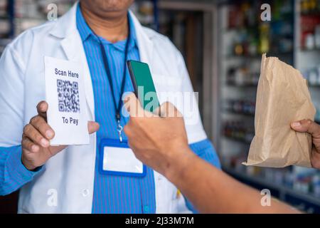 Nahaufnahme der Kundenhände, die durch Scannen des qr-Codes im Medizingeschäft für den Kauf von Medikamenten bezahlen - Konzept der bargeldlosen oder kontaktlosen Transaktion Stockfoto