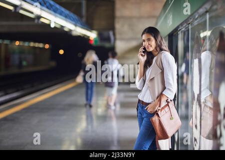 Sie kann die großartige Verbindung in der U-Bahn kaum glauben. Ausgeschnittene Aufnahme einer jungen attraktiven Frau, die auf einem Anruf und mit dem Zug pendelte. Stockfoto