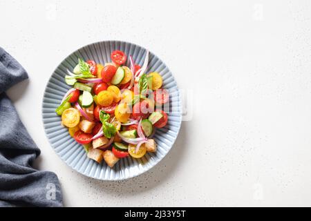 Toskanische Sommer-Panzanella mit Tomaten, knusprigem Brot, roter Zwiebel auf weißem Hintergrund mit Kopierraum. Draufsicht. Italienische Küche. Mittelmeer gesund Stockfoto