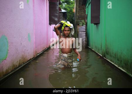 Ein Junge läuft am 15. Juli 2020 in Sunamganj im Nordosten Bangladeschs durch überflutetes Wasser. Jedes Jahr sind Millionen von Menschen von Überschwemmungen betroffen, die durch starke Regenfälle und überfließende Flüsse sowohl im Nordosten als auch im Nordwesten von Bangladesch verursacht wurden. Viele Menschen starben, vertrieben, verloren ihre Ernten, Häuser, litten während der Monsunflut unter Lebensmitteln und reinem Trinkwasser. Stockfoto