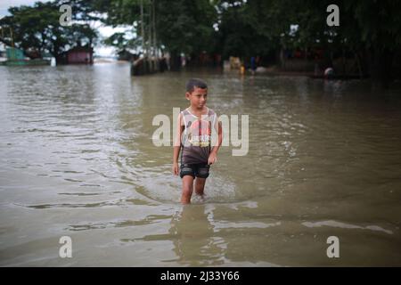 Ein Junge läuft am 15. Juli 2020 in Sunamganj im Nordosten Bangladeschs durch überflutetes Wasser. Jedes Jahr sind Millionen von Menschen von Überschwemmungen betroffen, die durch starke Regenfälle und überfließende Flüsse sowohl im Nordosten als auch im Nordwesten von Bangladesch verursacht wurden. Viele Menschen starben, vertrieben, verloren ihre Ernten, Häuser, litten während der Monsunflut unter Lebensmitteln und reinem Trinkwasser. Stockfoto