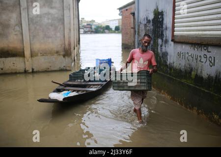 Am 15. Juli 2020 entlädt ein Mann Hühner aus dem Boot in einem überfluteten Gebiet in Sunamganj im Nordosten Bangladeschs. Jedes Jahr sind Millionen von Menschen von Überschwemmungen betroffen, die durch starke Regenfälle und überfließende Flüsse sowohl im Nordosten als auch im Nordwesten von Bangladesch verursacht wurden. Viele Menschen starben, vertrieben, verloren ihre Ernten, Häuser, litten während der Monsunflut unter Lebensmitteln und reinem Trinkwasser. Stockfoto