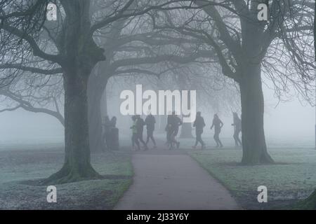 An einem kalten Morgen in Harrogate, England, trotzt eine vielseitige Gruppe von Joggern dem nebligen Wetter und joggt entlang der Stray, England, Großbritannien. Stockfoto