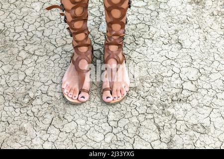 Nahaufnahme der Frauenbeine in Sandalen im römischen Stil Stockfoto