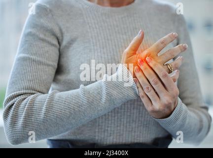 Ich habe zu lange getippt. Ausgeschnittene Aufnahme einer nicht erkennbaren Geschäftsfrau, die allein in ihrem Büro steht und unter einem Karpaltunnel leidet. Stockfoto