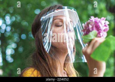 Junge Frau mit Gesichtsvisier, die ein Eis in der Hand hält Stockfoto