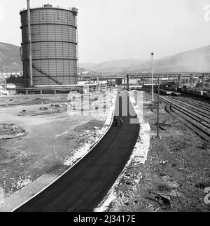 1950, historisch, das riesige Stahlwerk von Abbey Works im Bau, Bild zeigt eine neu verlegte Werkszufahrtsstraße neben den Eisenbahnschienen, Port Talbot, Wales, Großbritannien. Stockfoto