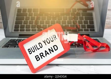 Erstellen Sie Ihren Markentext, der auf einem roten Namensschild auf einem Laptop oder Notebook angebracht ist. Stockfoto