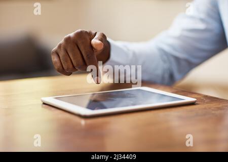 Eine Berührung und die Verbindung ist hergestellt. Ausgeschnittene Aufnahme eines nicht erkennbaren Geschäftsmannes, der in seinem Heimbüro ein Tablet verwendet. Stockfoto