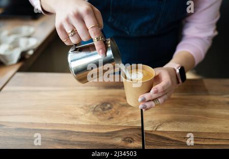 Der Prozess der Herstellung eines Barista Cappuccinos mit einem schönen Muster auf dem Schaum in einem Eco-Craft-Glas. Coffee to go-Konzept Stockfoto