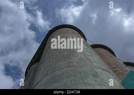 Getreideaufzug gegen einen stürmischen Himmel. Große Fabrikstruktur vor blauem Himmel, niedrige Sicht. Stockfoto