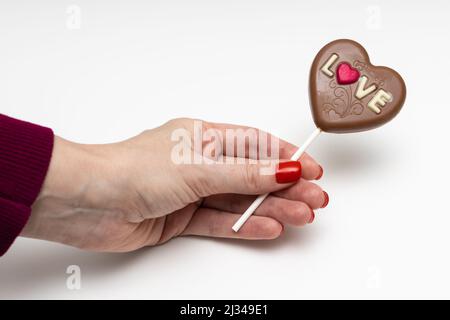 Frau, die eine Schokoladenbonbon in Form eines Herzens hält Stockfoto