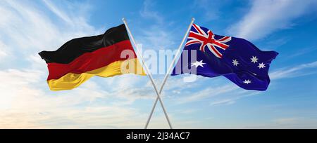 Zwei gekreuzte Flaggen Bundesrepublik Deutschland und Australien winken im Wind bei bewölktem Himmel. Konzept von Beziehung, Dialog, Reisen zwischen zwei Coun Stockfoto