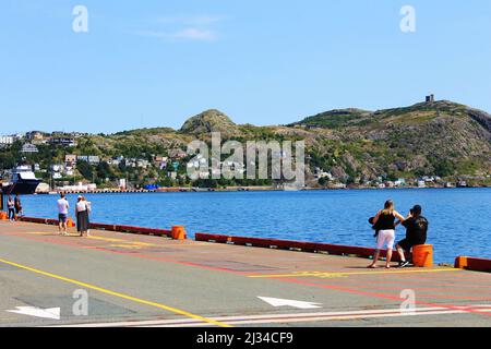 Menschen, die am Ufer des St. John's Harbour stehen und Fotos von Signal Hill machen. Stockfoto