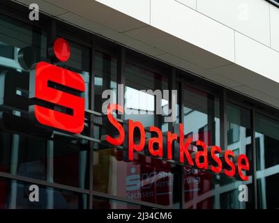 Sparkasse Bank Logo auf einer neuen Glasfassade. Reflexionen im Fenster und ein großes rotes Schild. Sparkassenfiliale in der Stadt. Business-Architektur Stockfoto