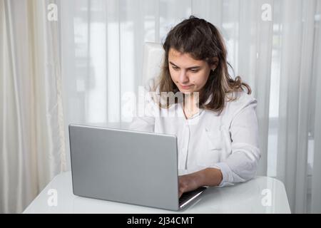 Eine behinderte Freiberuflerin arbeitet von zu Hause aus am Tisch auf einem Laptop Stockfoto