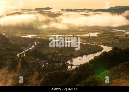 Luftaufnahme des Kok River bei Sonnenaufgang bedeckt Nebel Reisfelder im Tal und in den Bergen. Der Fluss entspringt in Myanmar. Stockfoto