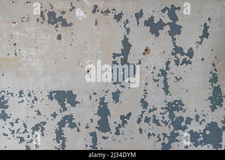 Graue Farbe an einer Wand, die abblättert. Abstrakter Hintergrund einer Vintage-Wand in einem verlassenen Gebäude. Innenarchitektur Textur einer Ruine. Hintergrund Stockfoto