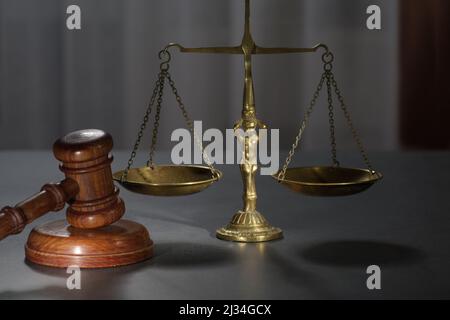 Hölzerne Richter gavel und Symbol für Recht und Gerechtigkeit auf dem Tisch in einem Gerichtssaal oder Strafverfolgungsbehörde auf dunklem Hintergrund Stockfoto