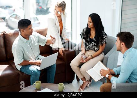 Ihre Ideen zusammenbringen, um etwas großartiges zu gestalten. Aufnahme einer Gruppe von Geschäftsleuten, die in einem Büro eine Diskussion führen. Stockfoto