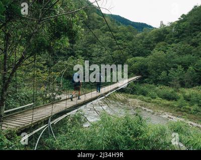 Zwei Wanderer überqueren eine Hängebrücke auf einem Wanderweg in Taiwan Stockfoto