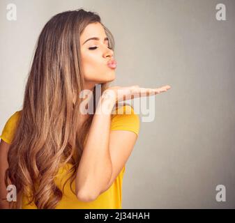 Ich habe nichts als Liebe für euch. Nahaufnahme einer ausdrucksstarken jungen Frau vor grauem Hintergrund. Stockfoto