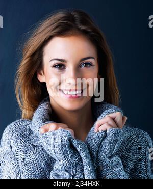 Bereit für den Herbst mit Stil. Studioportrait eines niedlichen Teenagers in einem Pullover, der vor dunklem Hintergrund posiert. Stockfoto