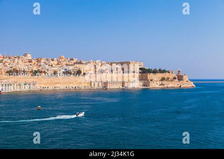 Valletta, Malta. Blick auf die Küste der maltesischen Hauptstadt an einem sonnigen Sommertag. Kleines Motorboot segelt das Meer Stockfoto